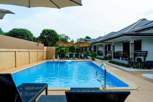 a swimming pool with chairs and umbrellas next to a house at Thai Smile Resort in Rayong
