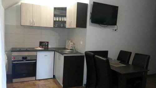 a small kitchen with a table and a tv on the wall at Eros apartmani in Zlatibor