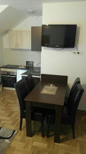 a kitchen with a wooden table and black chairs at Eros apartmani in Zlatibor