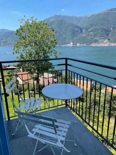 a table and chairs on a balcony with a view of the water at Il Noce Lake View Apartment in Lezzeno