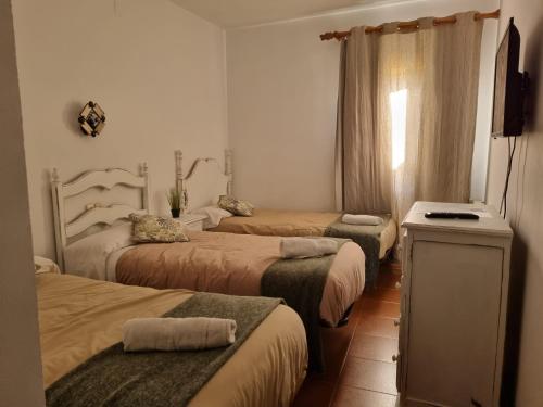 a hotel room with four beds and a television at NcantadaROOMS in Tragacete