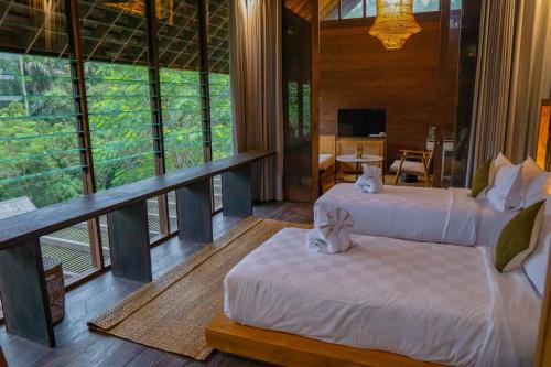 Zimmer mit 2 Betten und einem Balkon mit Tisch in der Unterkunft Hideaway Village Bali Ubud by Kanaan Hospitality in Ubud