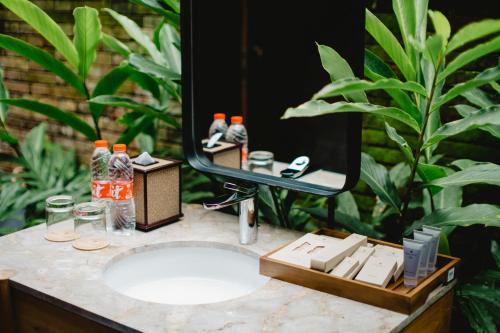 ein Waschbecken mit einem Spiegel darüber in der Unterkunft Hideaway Village Bali Ubud by Kanaan Hospitality in Ubud