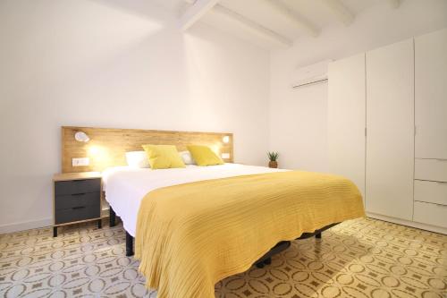 a bedroom with a large bed with a yellow blanket at Mediterranean Way - Cavaller Suites in Tarragona