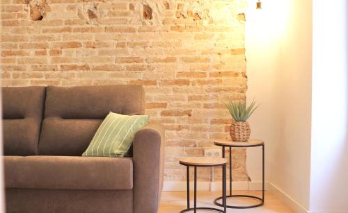 a couch and two tables in front of a brick wall at Mediterranean Way - Cavaller Suites in Tarragona