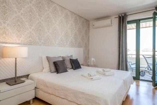 Schlafzimmer mit einem großen weißen Bett und einem Balkon in der Unterkunft VilamouraSun Aquamar 418 Vista Marin in Vilamoura