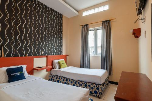 Cette chambre comprend 2 lits et une table. dans l'établissement Urbanview Hotel Syariah Residence Medan by RedDoorz, à Medan