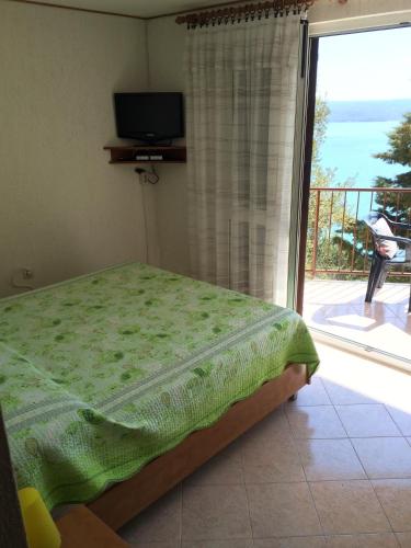 a bedroom with a bed and a balcony with a television at Apartment Bertossin Rovini in Mošćenička Draga