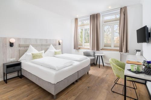 1 dormitorio con 1 cama blanca grande y escritorio en Parkhotel Wangerooge en Wangerooge