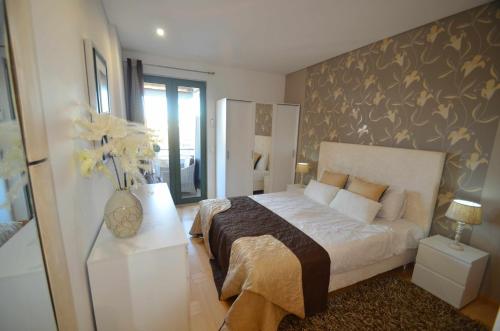 een slaapkamer met een groot bed en een vaas met bloemen bij Marina Vilamoura Aquamar 301 By Vilamoura Sun in Vilamoura