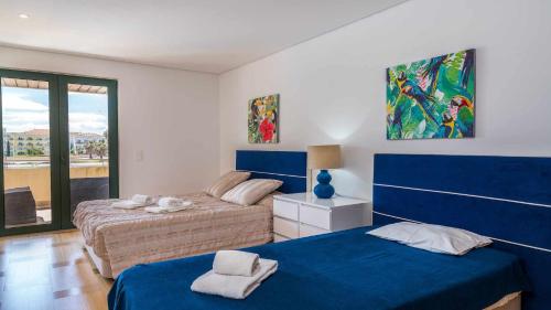 1 dormitorio con 2 camas con sábanas azules y ventana en VilamouraSun Aquamar 110 Pool and Marina View, en Vilamoura