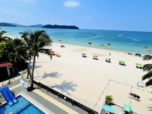 an overhead view of a beach with umbrellas and the ocean at Best Star Resort in Pantai Cenang