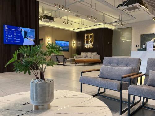 a waiting room with chairs and a table and a tv at FUHOTEL in Bukit Mertajam