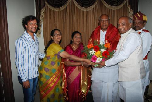 a group of people standing around a man holding a bouquet of flowers at Hotel MGM Grand in Srikalahasti