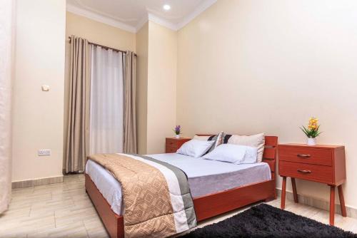 een slaapkamer met een bed en een houten nachtkastje met een lade bij SkyGrey suites in Kampala