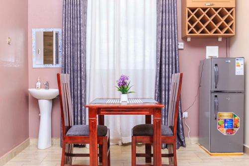 een eettafel en stoelen met een wastafel en een koelkast bij SkyGrey suites in Kampala