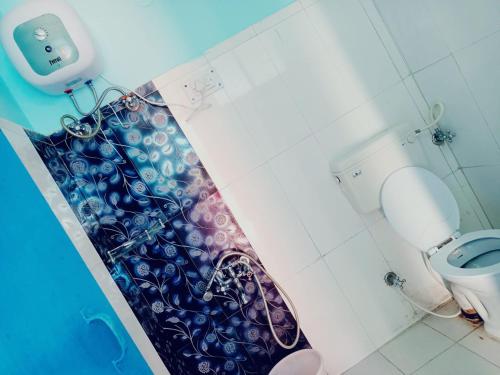 a bathroom with a shower curtain next to a toilet at The HappyTel in Mussoorie