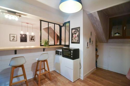 - une cuisine avec deux tabourets de bar et un four micro-ondes dans l'établissement Petit chez-vous rue Vaugelas, à Annecy