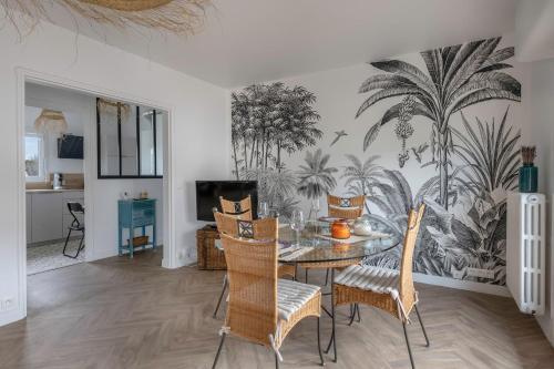 une salle à manger avec une table, des chaises et une fresque murale en palmier dans l'établissement Appartement à 650m de la plage !, au Pouliguen