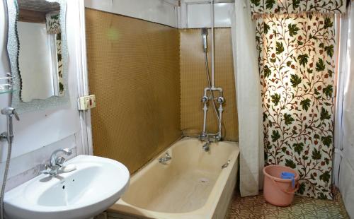 La salle de bains est pourvue d'un lavabo et d'une baignoire à côté d'un lavabo. dans l'établissement Houseboat Zaindari Palace, à Srinagar