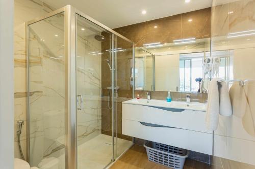 een badkamer met een wastafel en een glazen douche bij Marina View Apartment By VilamouraSun in Vilamoura
