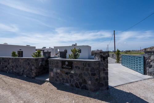 a house with a stone wall and a fence at Almira Luxury Suites in Perivolos