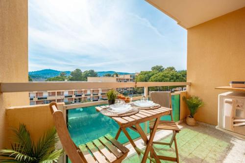 a balcony with a table and chairs and a pool at Cabana & Le Mimosa Ensoleillé - Plage, Box, Terrasse in Bormes-les-Mimosas