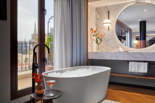 Kimpton Vividora Hotel by IHG في برشلونة: حمام مع حوض استحمام ومرآة كبيرة