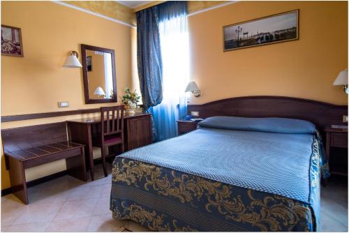 a bedroom with a bed and a desk and a mirror at B&B Degli Amici in Ciampino