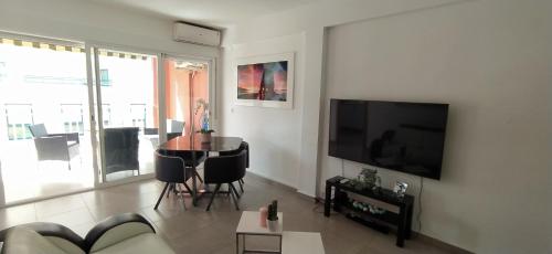 ein Wohnzimmer mit einem Tisch und einem TV in der Unterkunft Apartamento NAVI II playa de Gandia para 6 personas in Playa de Gandia