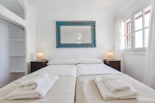 a white bedroom with two beds and a mirror at BAHÍA DE EL PORTET - By Almarina Villas in Moraira