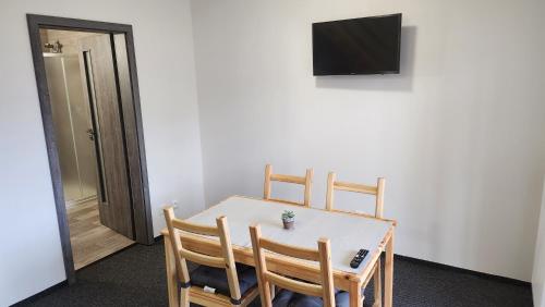 a dining room table with three chairs and a television at Penzion-Dubno in Dubno