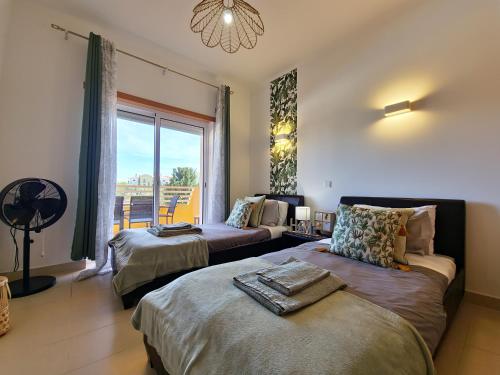 a bedroom with two beds and a large window at Apartamento Royal Garden T2 by YHA in Conceição