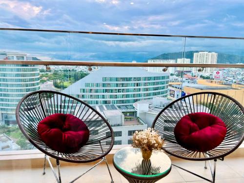 two chairs with red pillows sitting on a balcony at The Sóng Vũng Tàu - Mochi House in Vung Tau