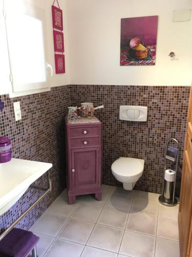 ein Badezimmer mit einem lila Schrank und einem WC in der Unterkunft La chambre haute et son spa in Nîmes