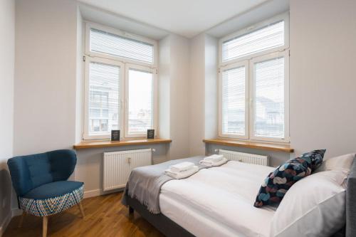 Schlafzimmer mit einem Bett, einem Stuhl und Fenstern in der Unterkunft Luxury Apartments Nearto Main Square in Krakau