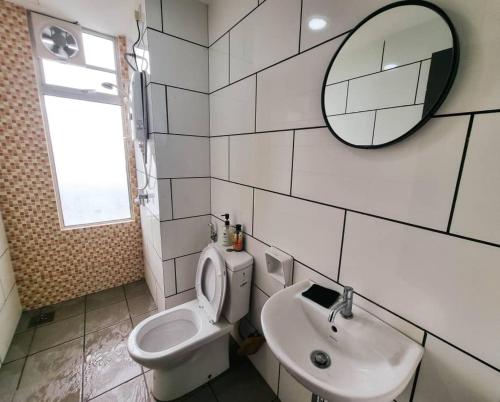 a bathroom with a toilet and a sink and a mirror at Taiping Centre Point Suite 10 by BWC in Taiping