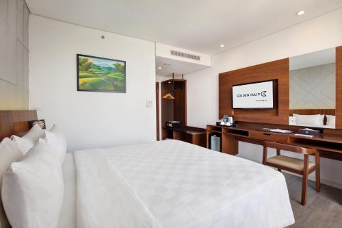 a bedroom with a bed and a desk and a television at Golden Tulip Pontianak in Pontianak