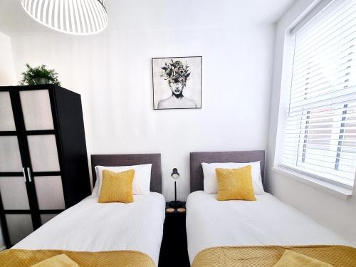 2 letti in una camera con pareti bianche e cuscini gialli di STYLISH 2 Bed APARTMENT WITH FREE PARKING, WIFI a Colchester