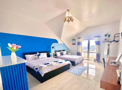 a bedroom with two beds and a blue wall at Bear Brick Villa in Da Lat