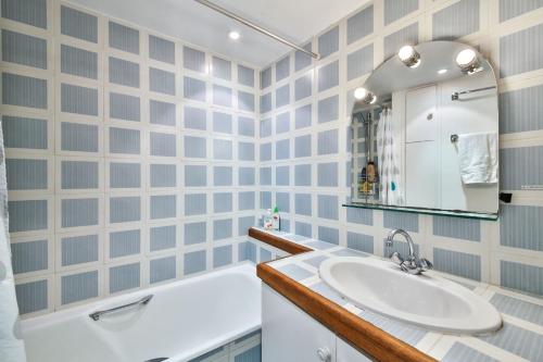 une salle de bain avec un lavabo, une baignoire et un miroir dans l'établissement Séguier proche Seine, à Paris