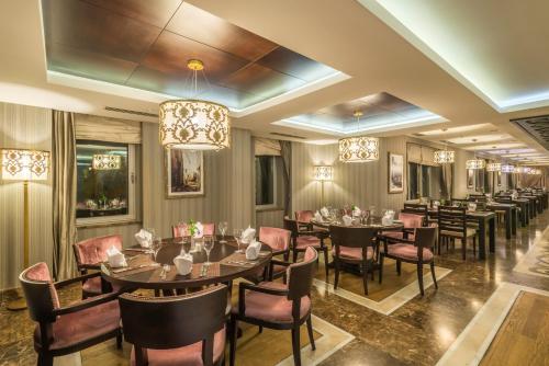 a dining room with tables and chairs and a chandelier at Badamdar Hotel and Residences in Baku
