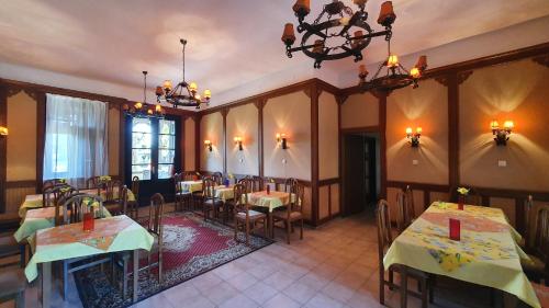 a restaurant with tables and chairs and a chandelier at Harmónia Apartmanház in Balatonlelle