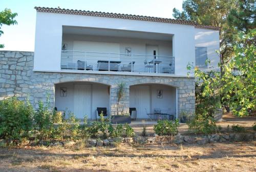 Casa blanca con balcón y árboles en L'UMBRIA, en Calvi
