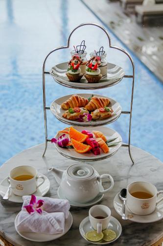 a table with plates of food and cups of coffee at Paris Deli Danang Beach Hotel in Da Nang