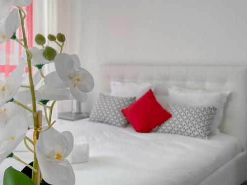Cama blanca con almohadas y almohada roja en Mango balcon 5 min de la vieille ville, en Annecy