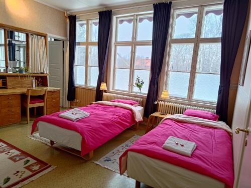 Perrongen Guesthouse في Munkfors: غرفة نوم بسريرين ومكتب ونوافذ