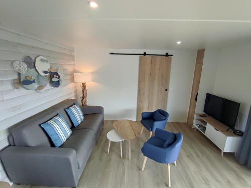 - un salon avec un canapé, deux chaises et une télévision dans l'établissement Atlantic Lodge, à Bretignolles-sur-Mer
