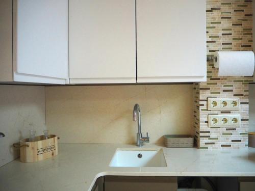 een keuken met witte kasten en een wastafel bij Cal Xambu in Cambrils