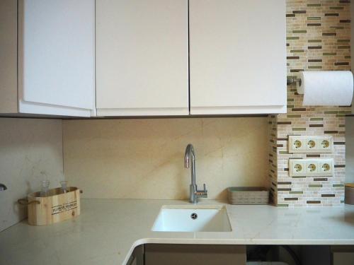 a kitchen with white cabinets and a sink at Cal Xambu in Cambrils